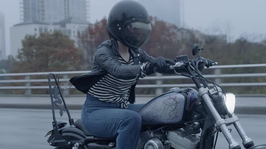 A woman rides a motorcycle on a city highway