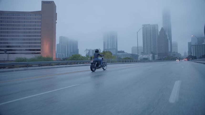 A motorcyclist rides on a rain covered road