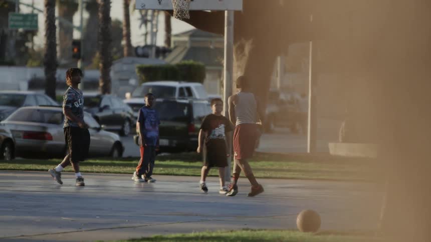 Children play basketball in a busy city