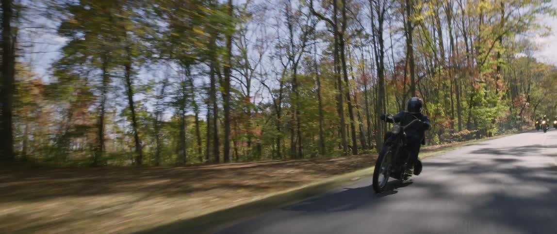 A motorcyclist rides through a forest