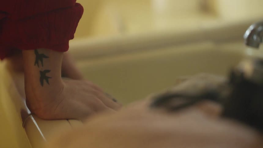 A woman leans over a bathroom sink