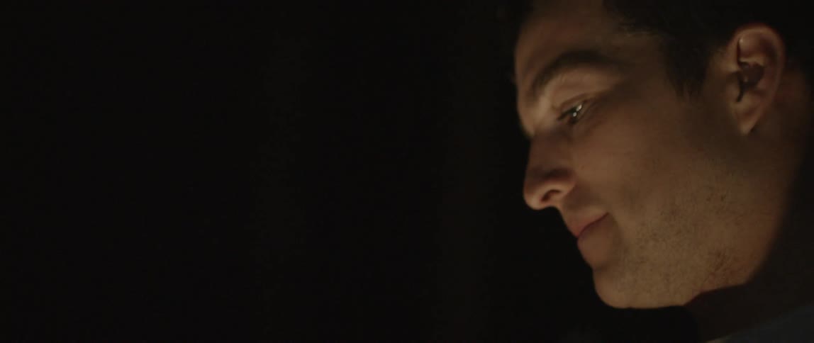 A man smiles and laughs outside at night