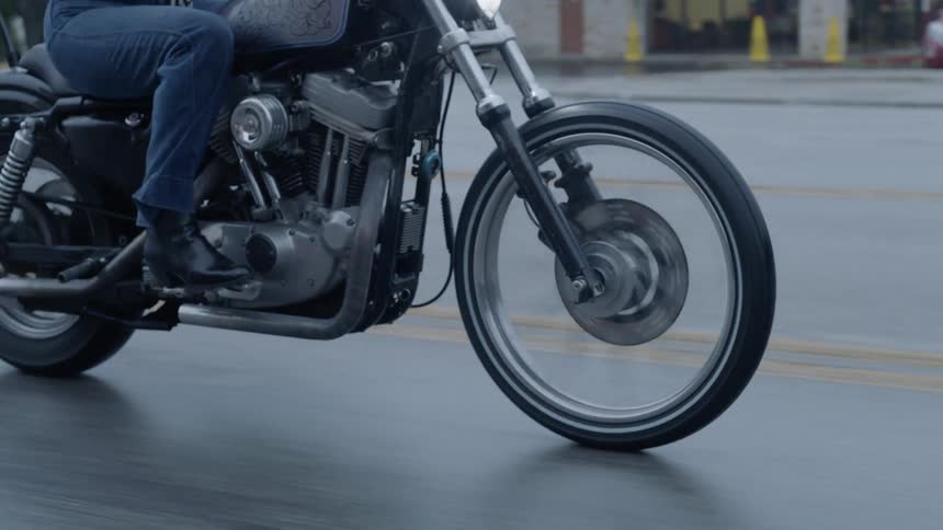 A person is riding a motorcycle on a wet road at dusk