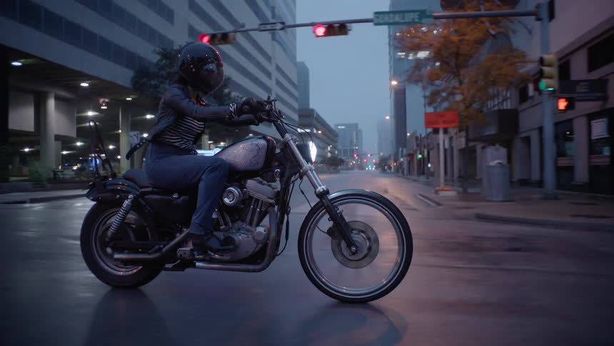 A motorcyclist rides on a city street in the rain