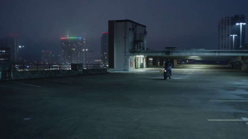 A person is riding a motorcycle on a roof top parking lot