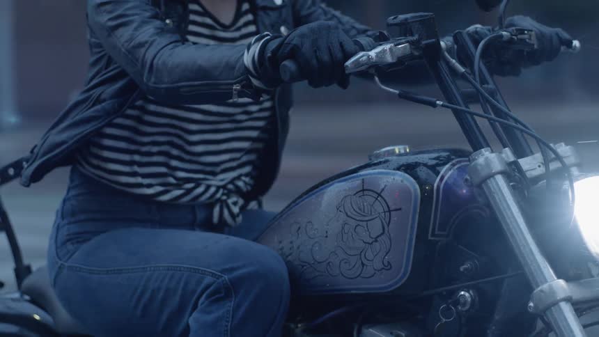A woman rides a motorcycle in the rain