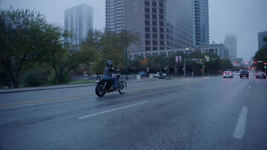 Person rides a motorcycle towards the city