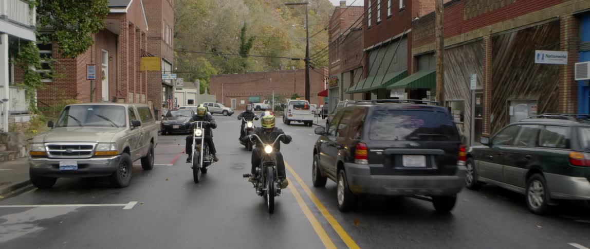 Four motorcycles ride down a town's main street