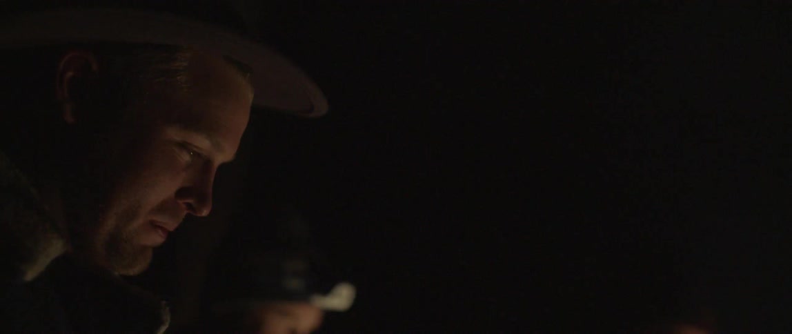 A man laughs next to a campfire at night