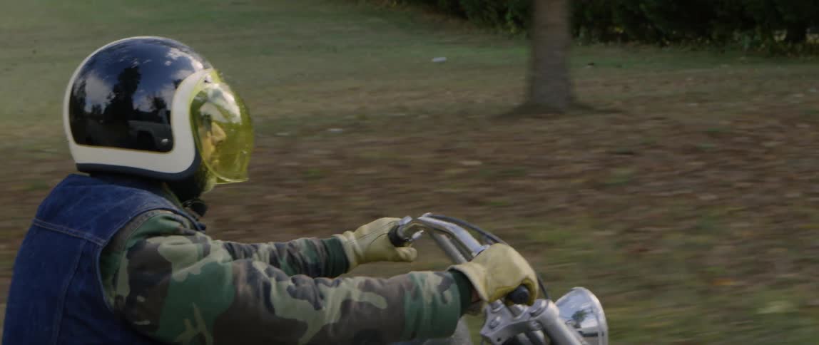 A man is riding a motorcycle outside during the day