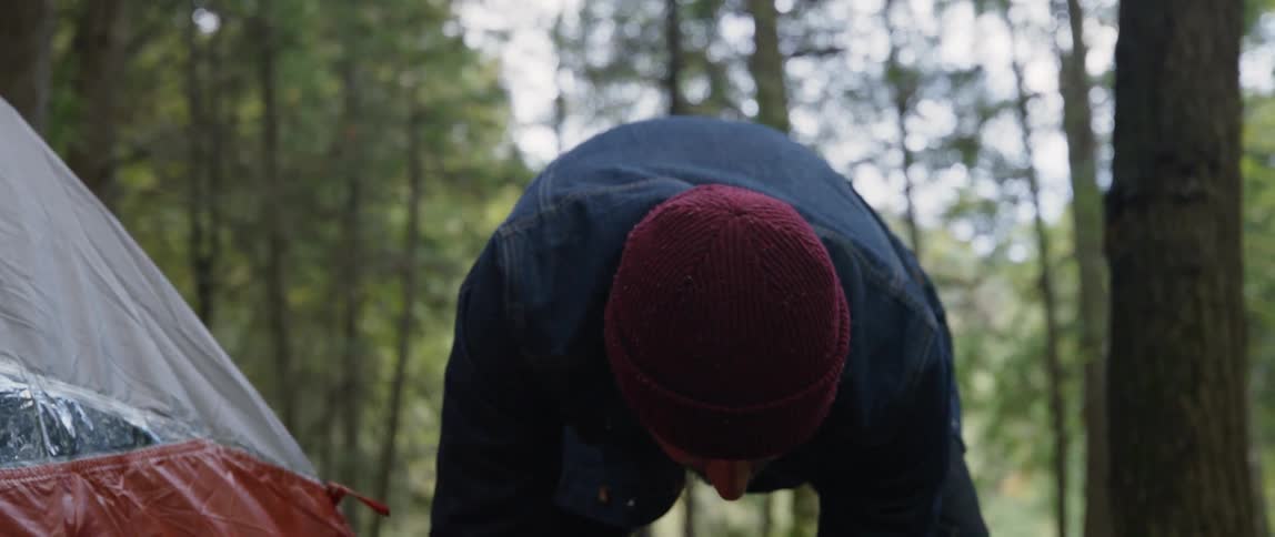 A man pitches a tent in the woods