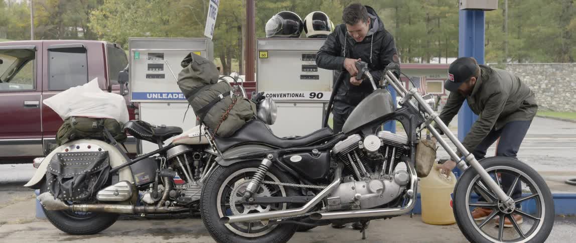 A man puts gas in a motorcycle at a gas station