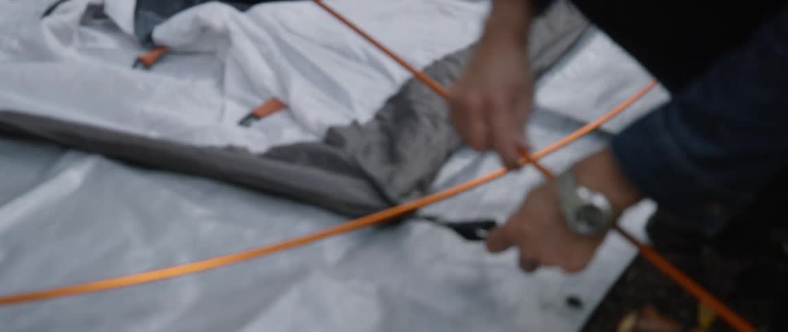A man sets up a tent in the woods