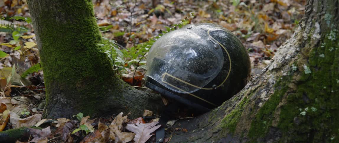 A helmet sits on a forest floor