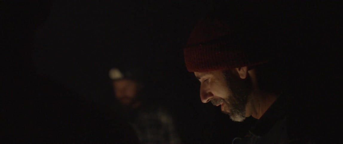 Two men converse and laugh together outside at night