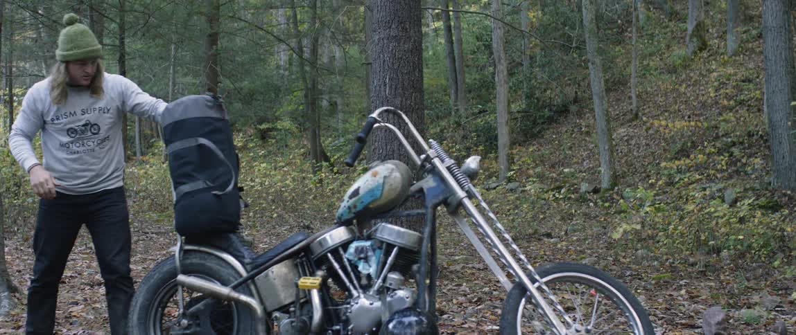 A man is strapping a pack to his motorcycle