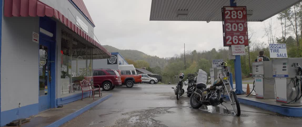 Motorcycles are parked at gas pumps at a gas station