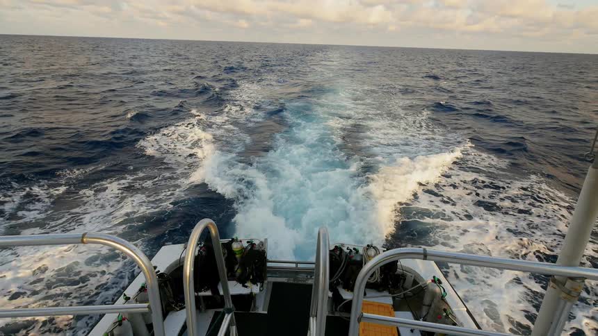 A large boat travels through the ocean with clouds in the sky