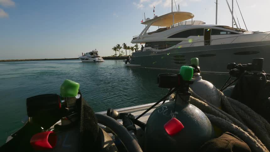 Air tanks sit in the back of a motor boat traveling around docked ships