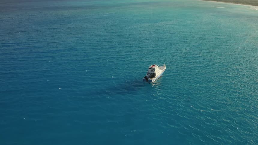 A fishing boat is sailing off an island coast during the day