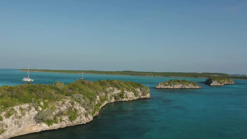 Boats float near islands on the ocean