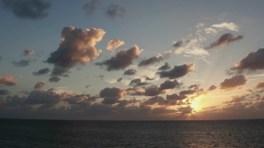 The sun is casting rays as it sets over the ocean