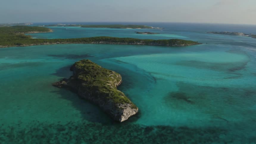 Ocean waters are flowing and lapping around an island chain on a sunny day