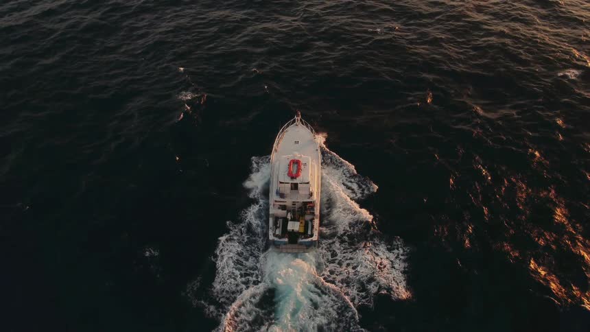 A boat sails on the ocean at sunset