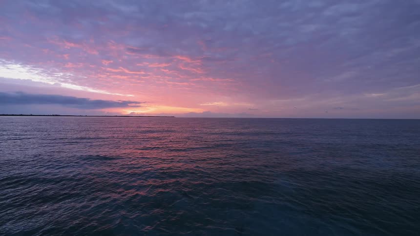 The tide is rolling in the ocean at sunset