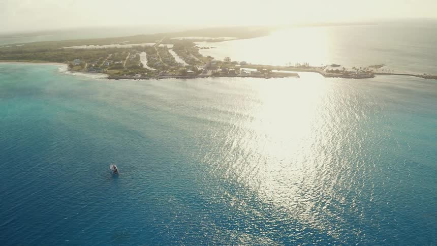 A boat is floating in the ocean off an island coast in daylight