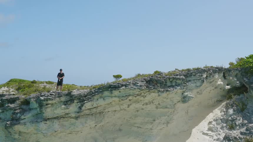 A person stands at the edge of a cliff