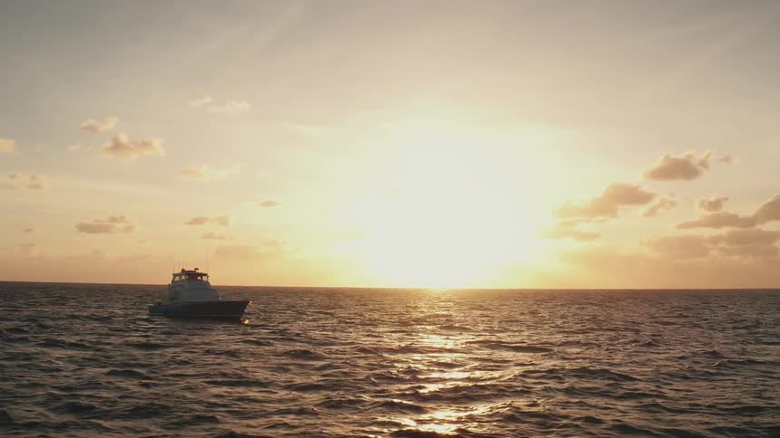 The sun shines on glistening water as a boat rocks in the waves