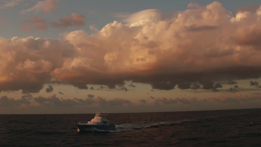 A boat sails on the ocean at sunset