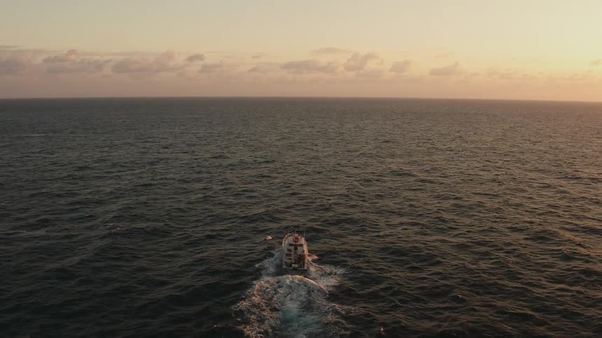A boat sails on the ocean at sunset