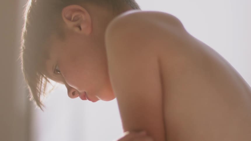 A boy is sitting on the ground in a room playing during the day