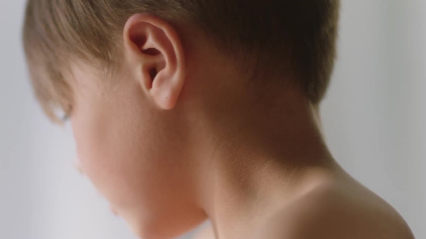 A boy is moving his head as he plays in a room during the day