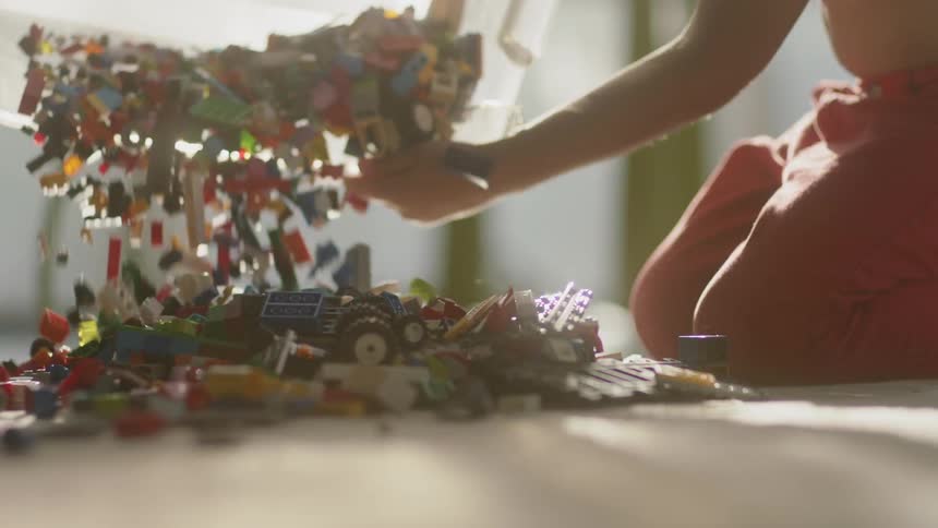 A young child dumps building blocks onto the floor
