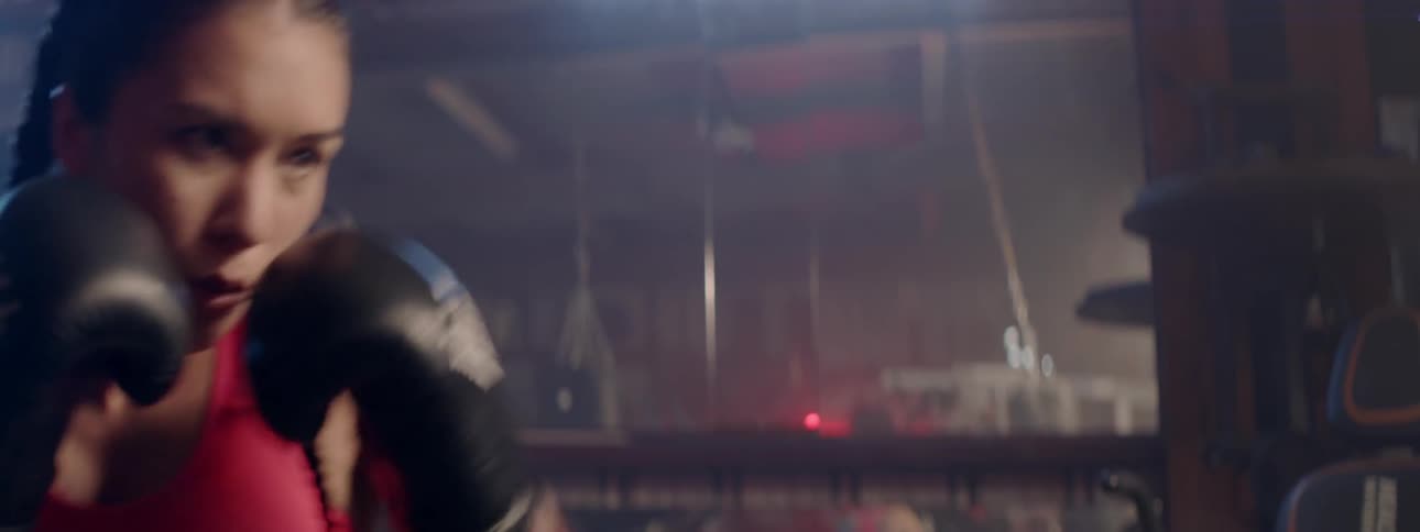 Woman using a heavy bag to exercise and train on boxing