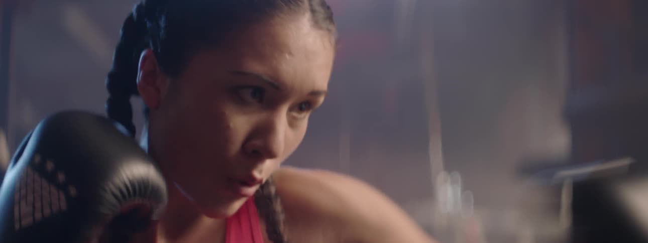 A woman wearing boxing gloves hits the heavy bag