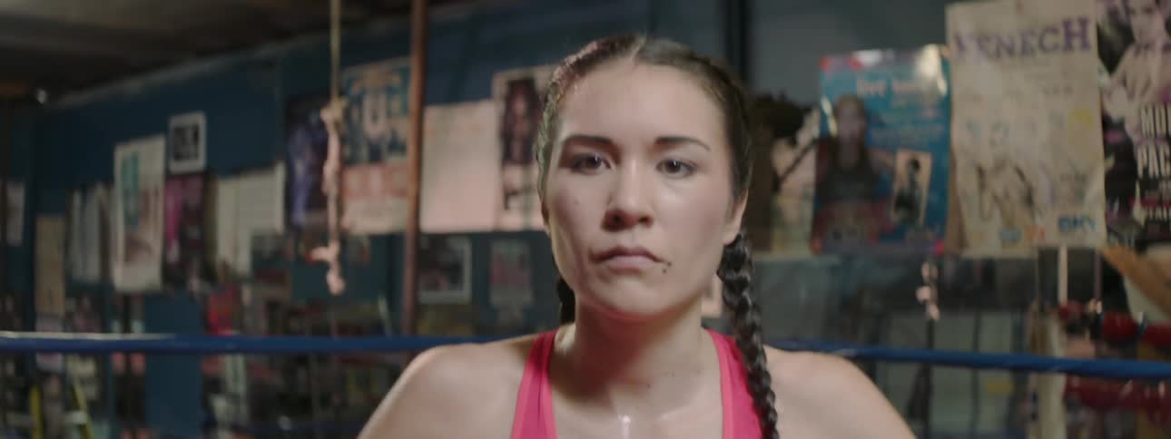 A female boxer hits her chest in a boxing ring