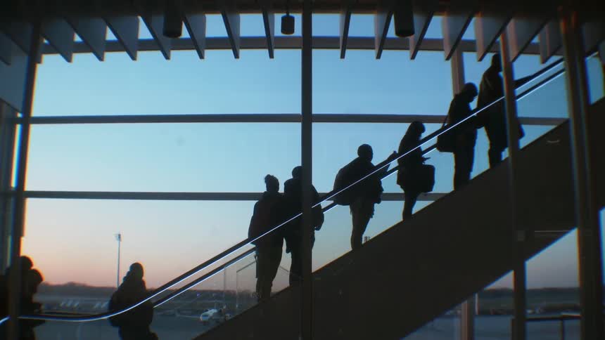 People are going up an escalator at an airport at dusk