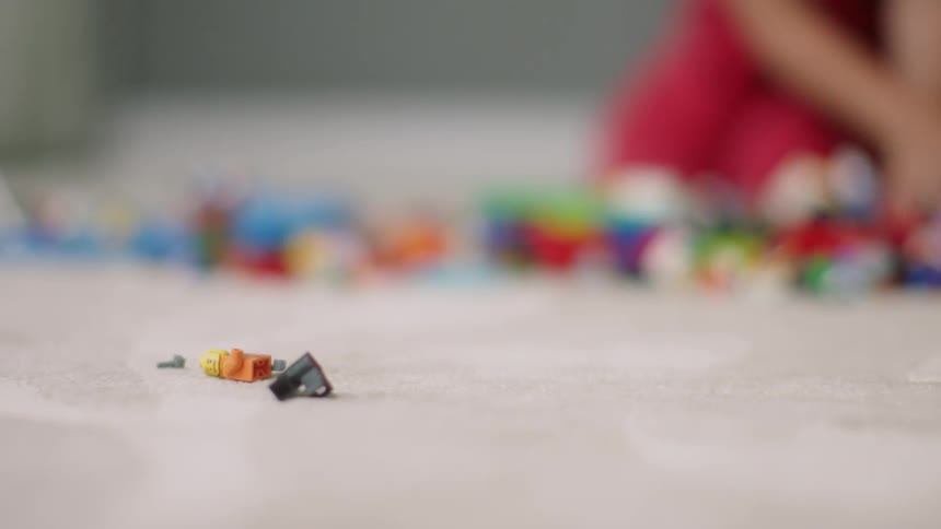 A child is playing in a room with many pieces of building block bricks and toys