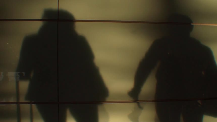 Shadows of people are cast onto a wall