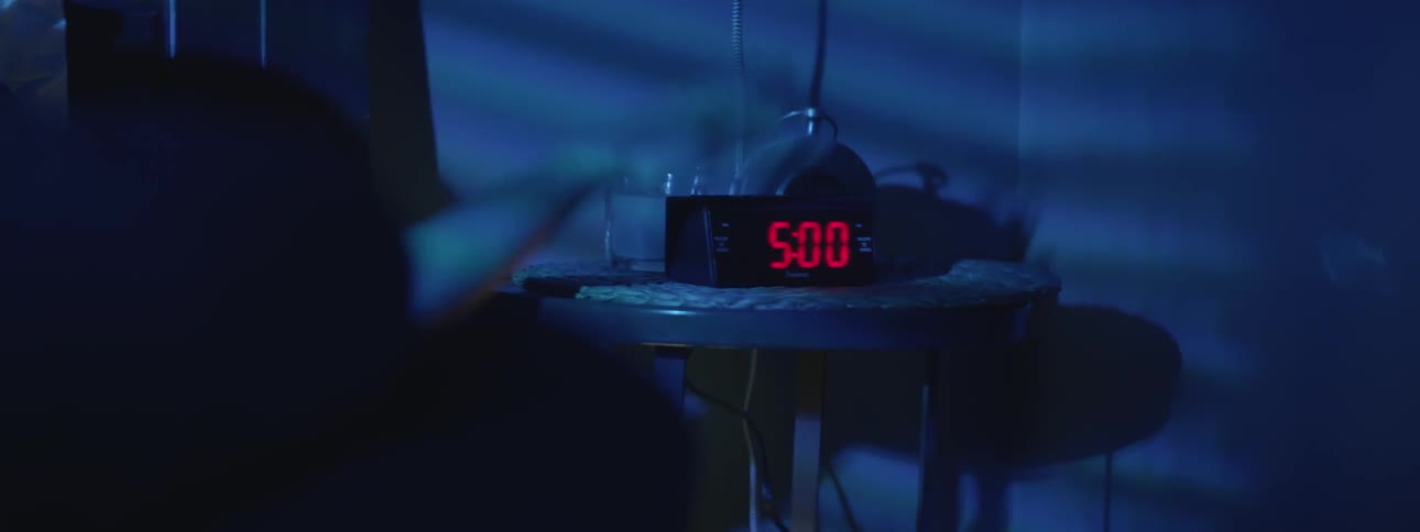 A hand reaches out of bed and hits the snooze alarm