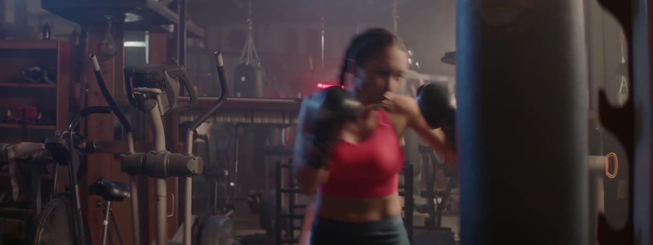 Woman wearing boxing gloves strikes a punching bag