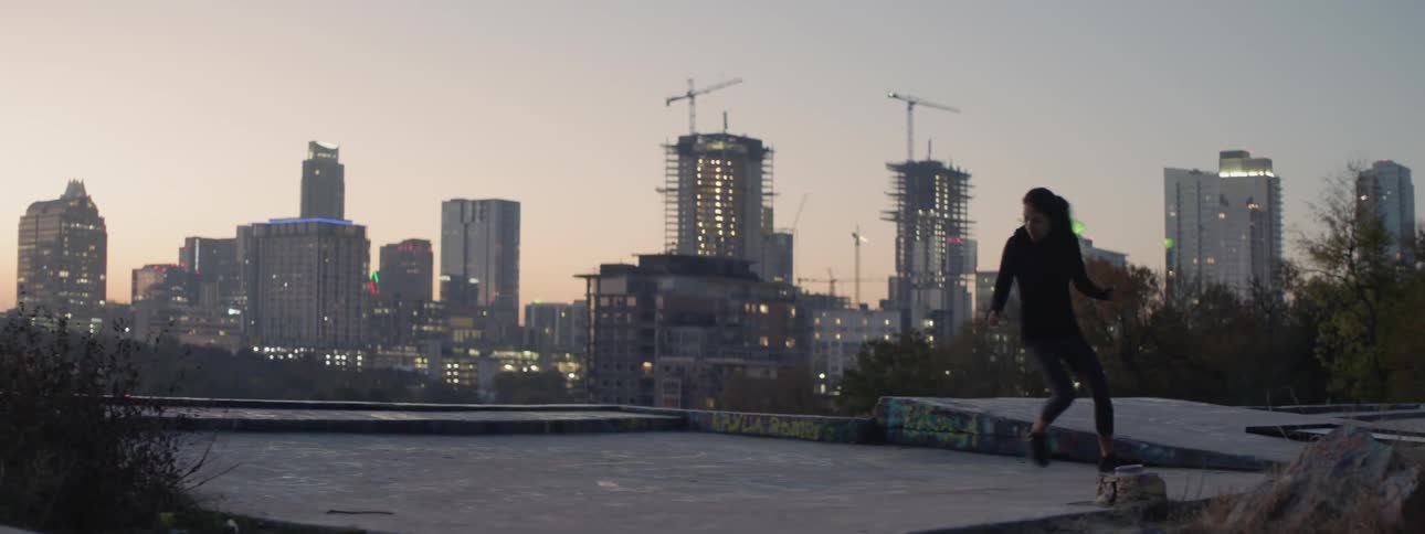 Woman exercising on a rooftop by rapidly moving side to side using short quick steps at sunrise in a city