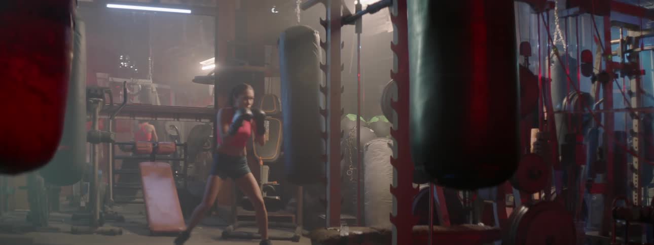 A female boxer is boxing a heavy bag in a gym