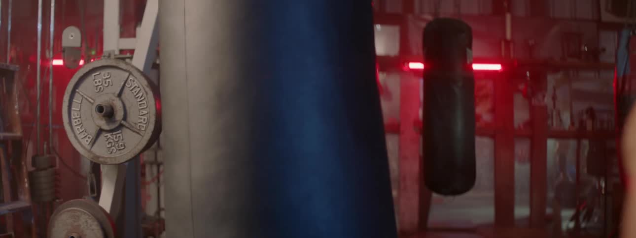 A female boxer is punching a bag in a gym then walking away