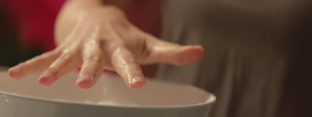 A female athlete is soaking her fingers in an ice bath and then flexing them