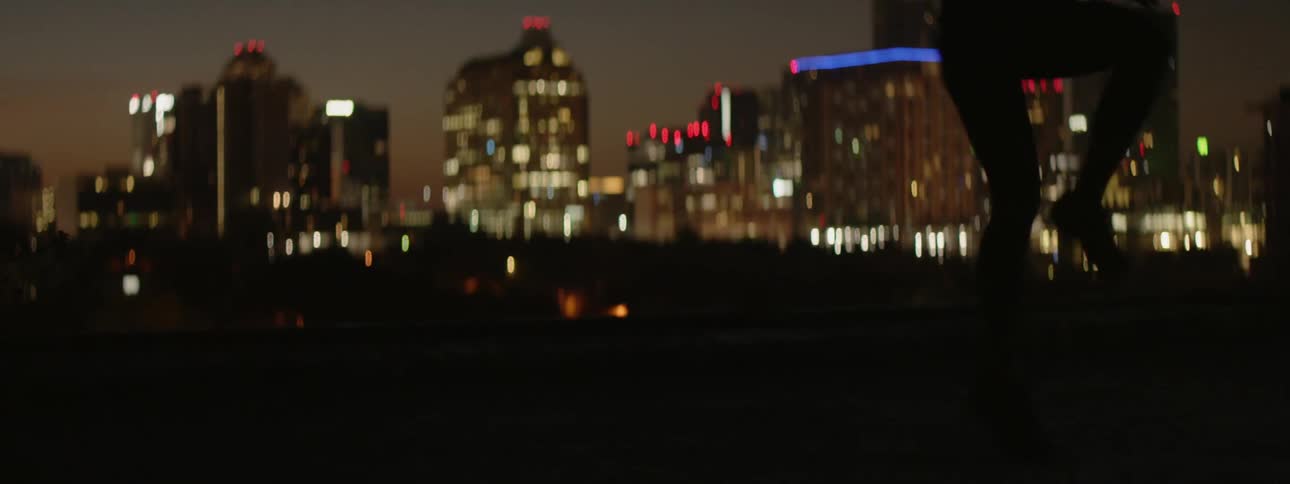 A female athlete is training on the outskirts of a city at night